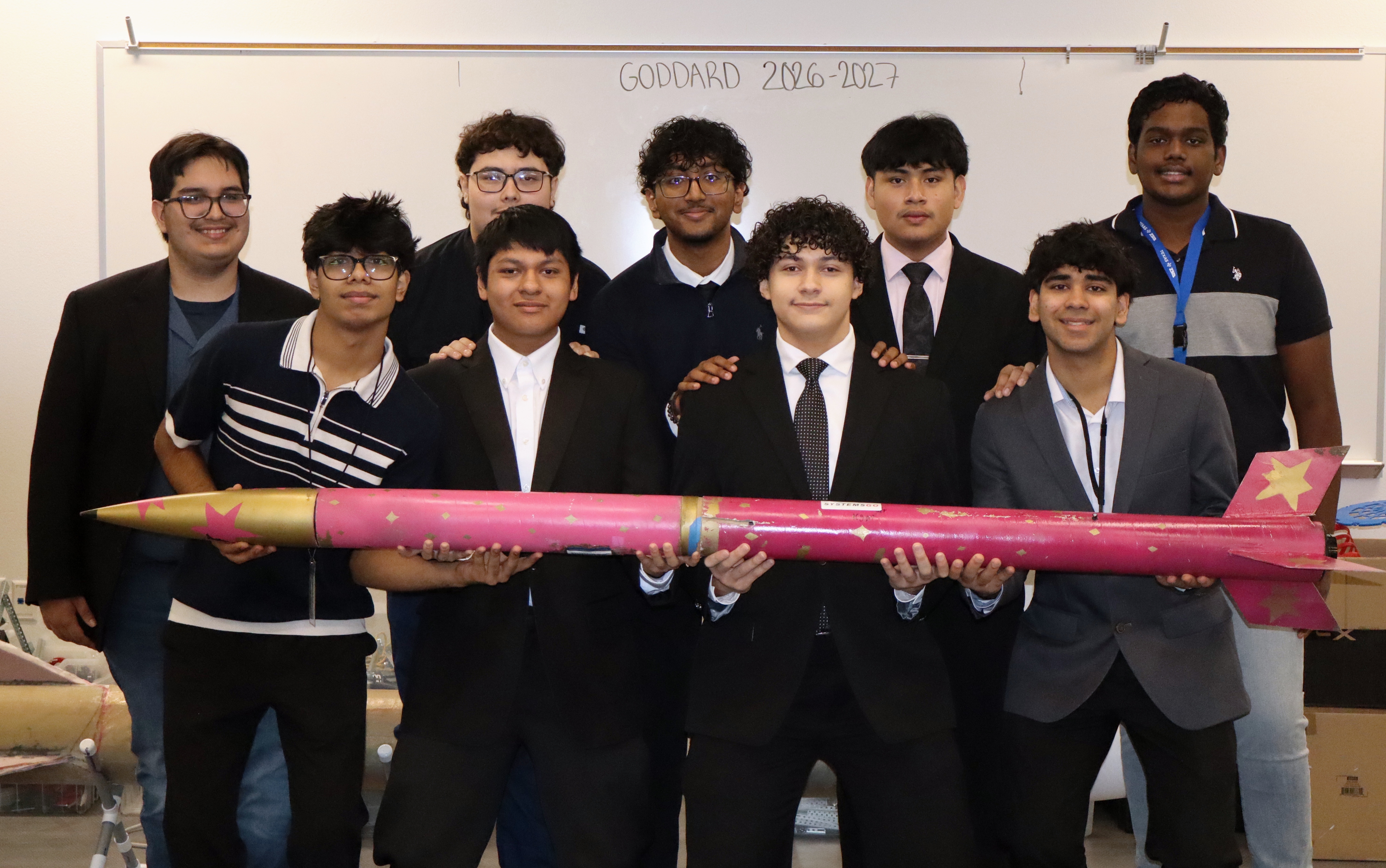 The I.T.E Goddard team holding a pink and gold rocket